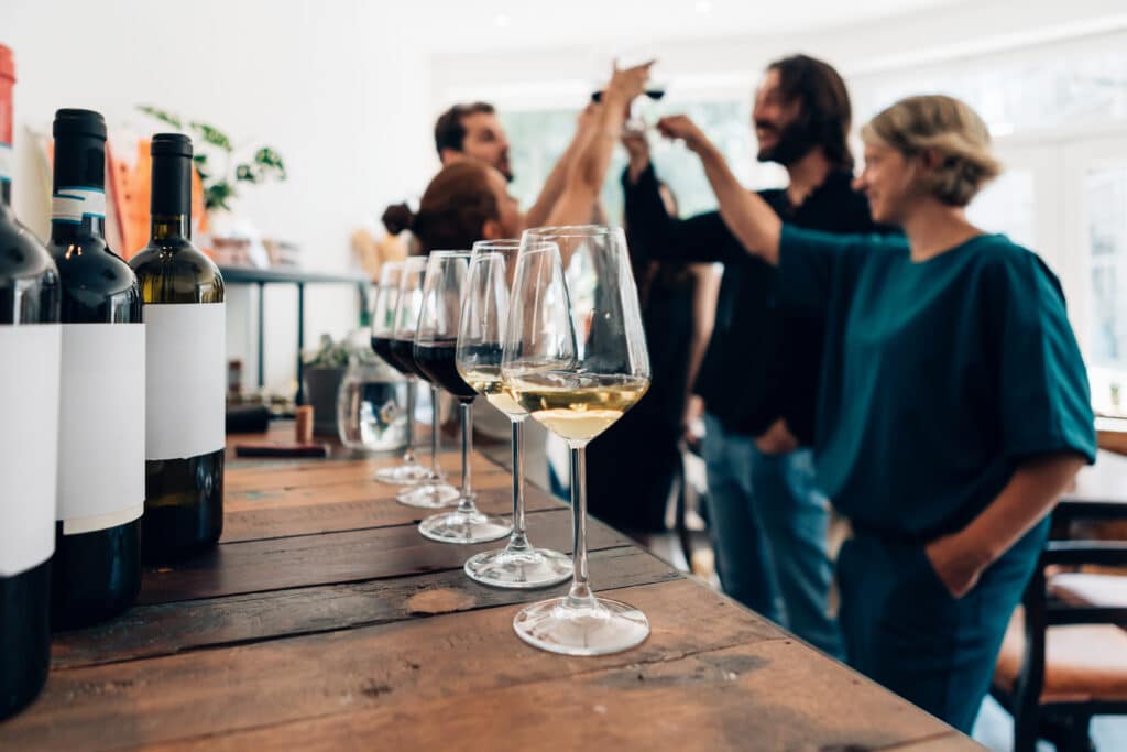 friends talking and drinking in a winery - Millennials toasting at a wine tasting