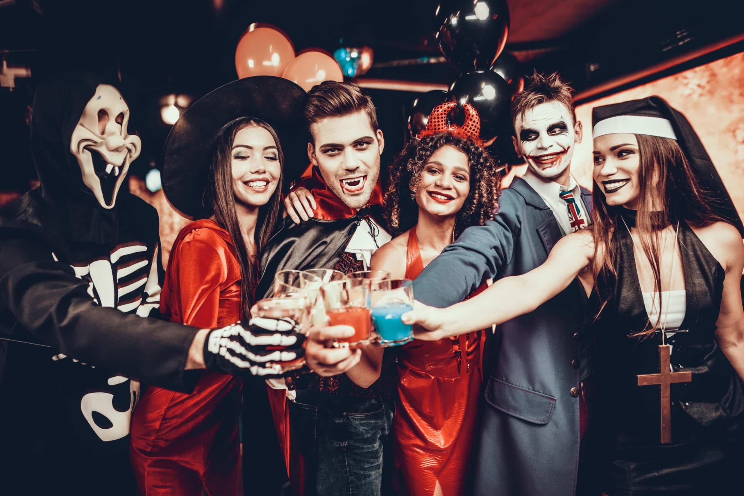 a group of friends clinking glasses in halloween costumes